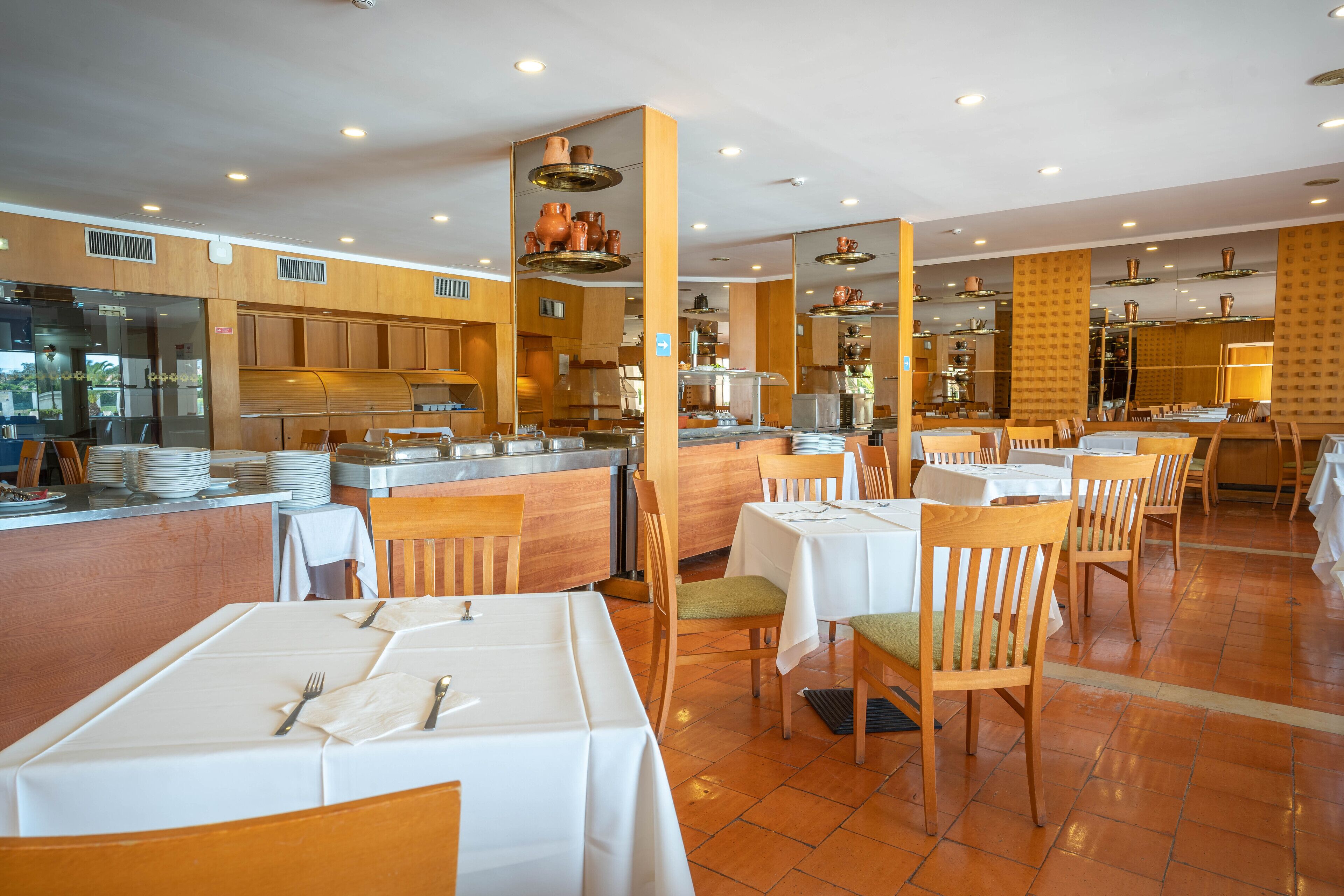 A restaurant with multiple tables and chairs, a kitchen area, and a counter.