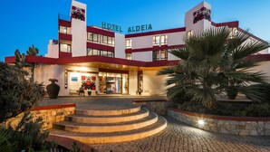 A hotel with a modern design, featuring a prominent entrance with steps leading up to the main doors, and a well-lit facade. - Hotel da Aldeia - Adults Only (Albufeira)