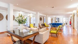 A spacious lobby with a glass coffee table, a sofa, and multiple armchairs. - Hotel da Aldeia - Adults Only (Albufeira)