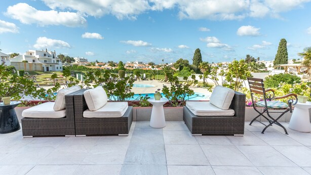 A rooftop terrace with wicker furniture, a pool, and a view of the city. - Hotel da Aldeia - Adults Only (Albufeira)