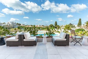 A rooftop terrace with wicker furniture, a pool, and a view of the city. - Hotel da Aldeia - Adults Only (Albufeira)