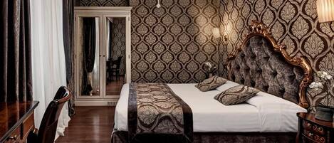 Quarto com cama grande, candelabro, papel de parede estampado e espelho.