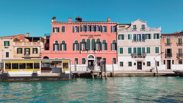 A row of historic buildings along a canal, including a pink building labeled "HOTEL TRE ARCHI". - Hotel Tre Archi (Venice)