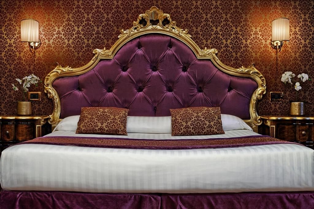 Ein Bett mit einer gesteppten Kopfteil, zwei Zierkissen und einer passenden Bettdecke.