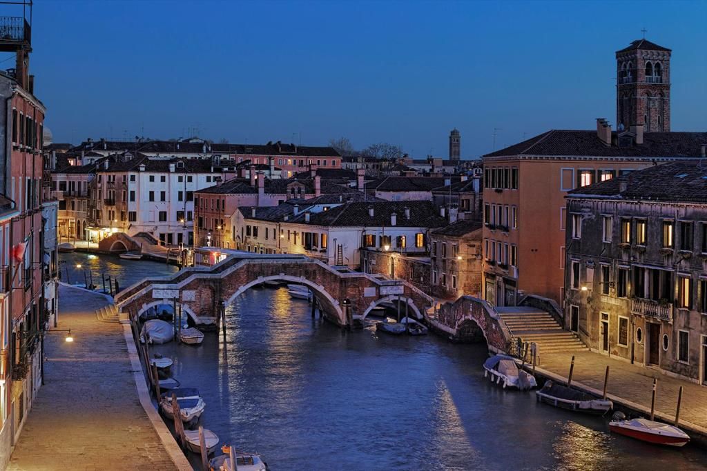 Un canal amb vaixells, un pont i edificis al costat de l'aigua.