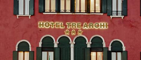 A building facade with multiple arched windows and a sign reading 'HOTEL TRE ARCH.'