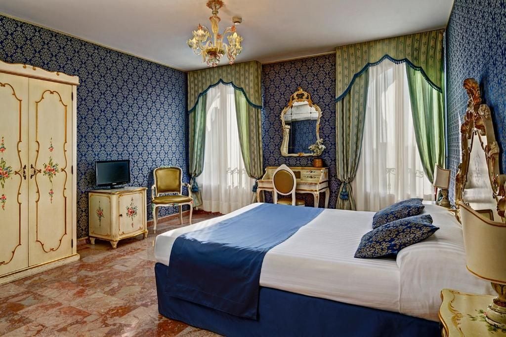 Une chambre à coucher avec un grand lit, une télévision, un bureau et une armoire.