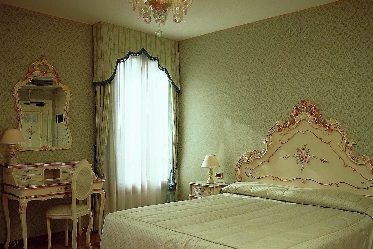 Une chambre à coucher avec un grand lit, un bureau avec une chaise, une commode et un lustre.