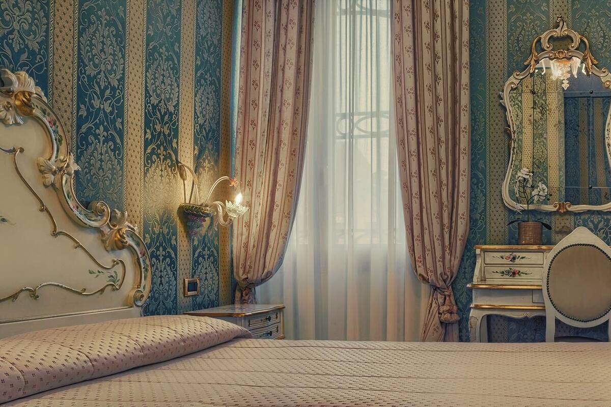 Une chambre à coucher comprenant un lit, une table de chevet, une commode, un miroir et des rideaux.