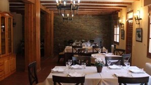 A dining area with wooden beams, stone walls, and tables set for dining.