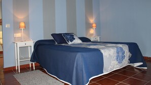 A bedroom with a bed, two bedside tables, and two wall-mounted lamps.