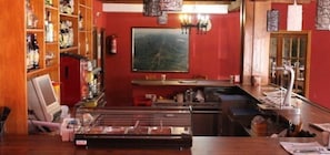 A bar area with a counter, shelves with bottles, a fire extinguisher, and a painting on the wall. - Hotel Valle del Jerte Los Arenales (Jerte)