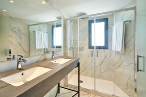 Features a large sink, glass-enclosed shower, and a large mirror.