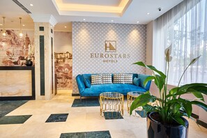 Relax in the stylish lobby, featuring a reception desk, comfortable sofa, and lush greenery.