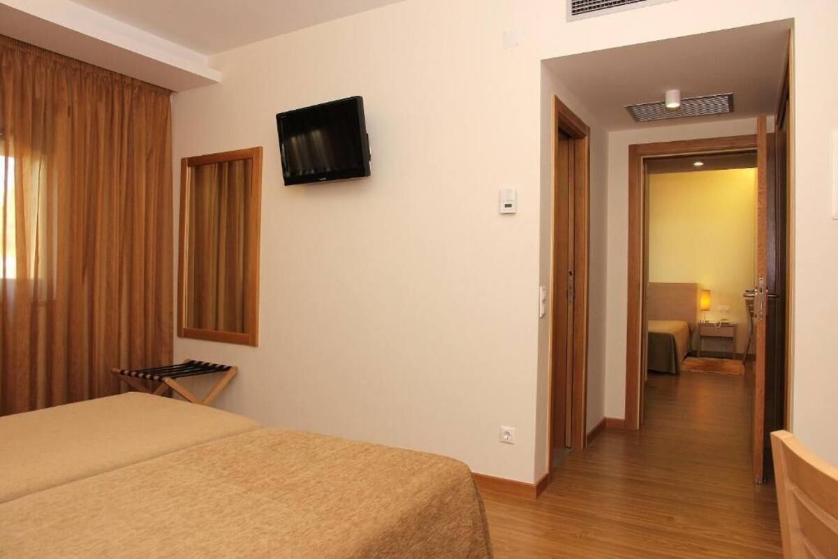 Ein Hotelzimmer mit einem Bett, einem an der Wand befestigten Fernseher und Holzboden.