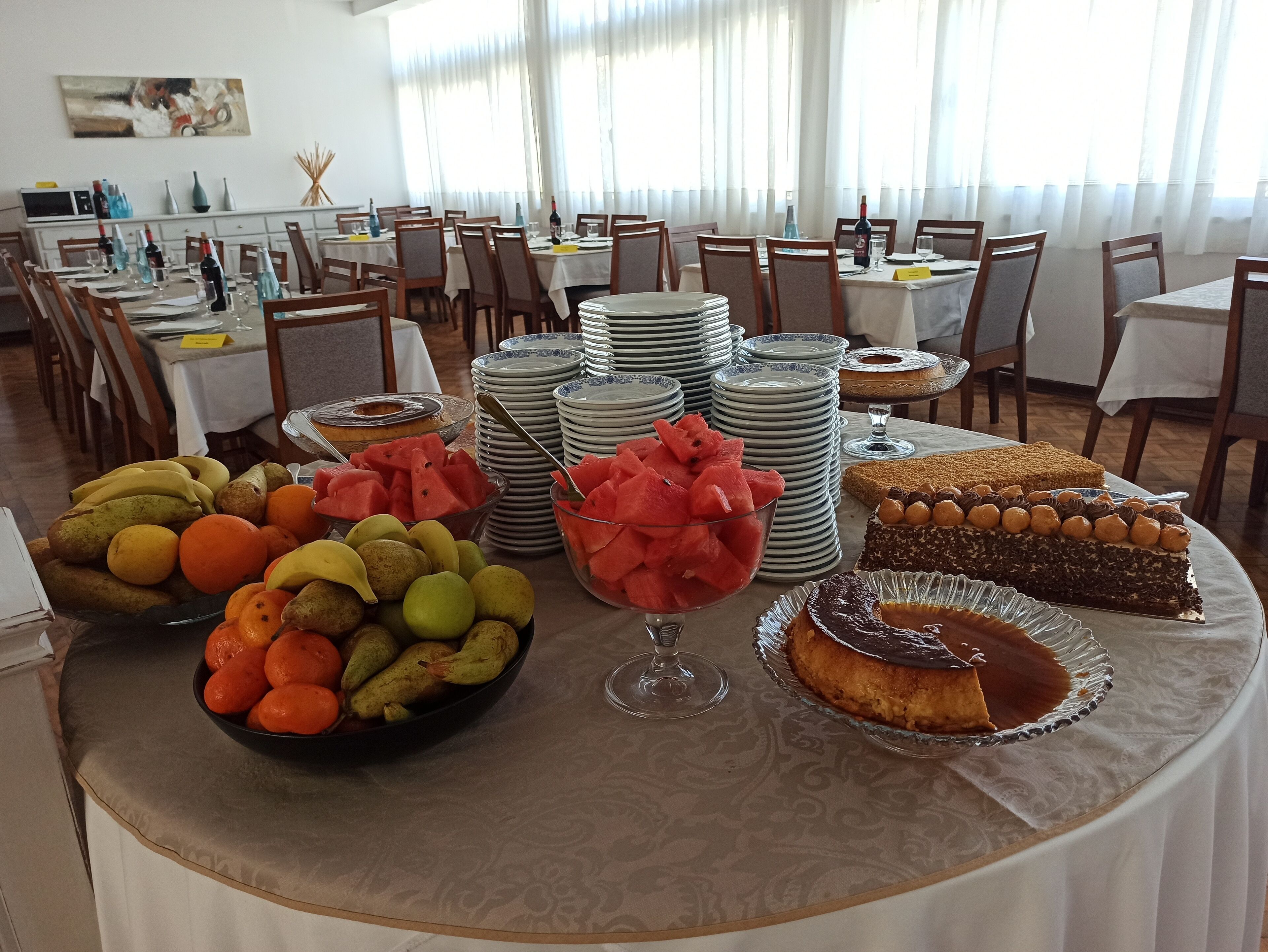 A buffet table with various fruits, a watermelon bowl, and several desserts.