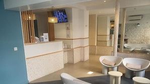 Un área de recepción con mostrador, asientos y televisor.