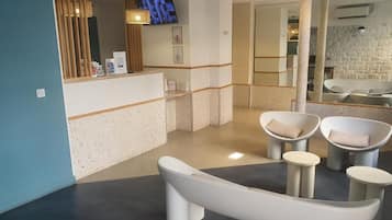 Aula, jossa on vastaanottotiski, istuimia ja televisio.