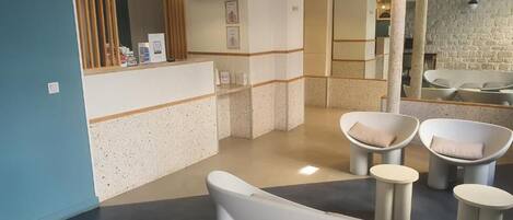 Un área de recepción con mostrador, asientos y televisor.