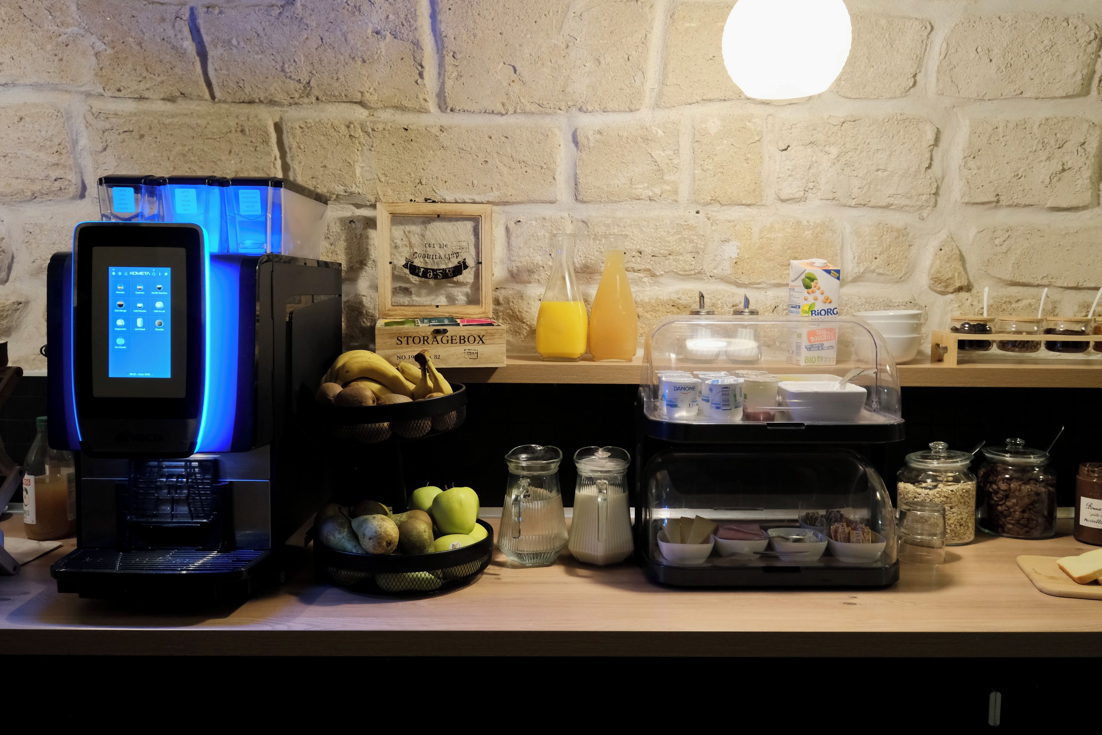 A kitchenette with a coffee machine, a fruit basket, and various food containers.