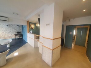 A modern interior with a reception desk, a stone wall, and a bathtub. - Hipotel Paris Père Lachaise République (Paris)