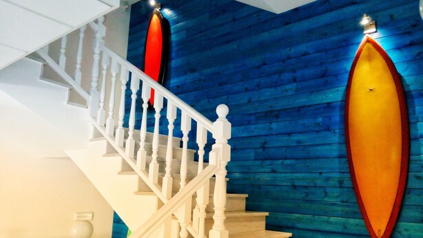 Uma escada com balaústres brancos e parede de madeira azul.