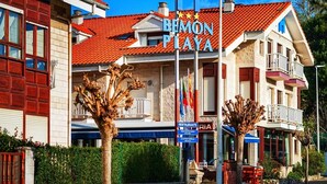 Um hotel chamado Bimon Playa, com telhado de telhas vermelhas, uma placa e uma bandeira.