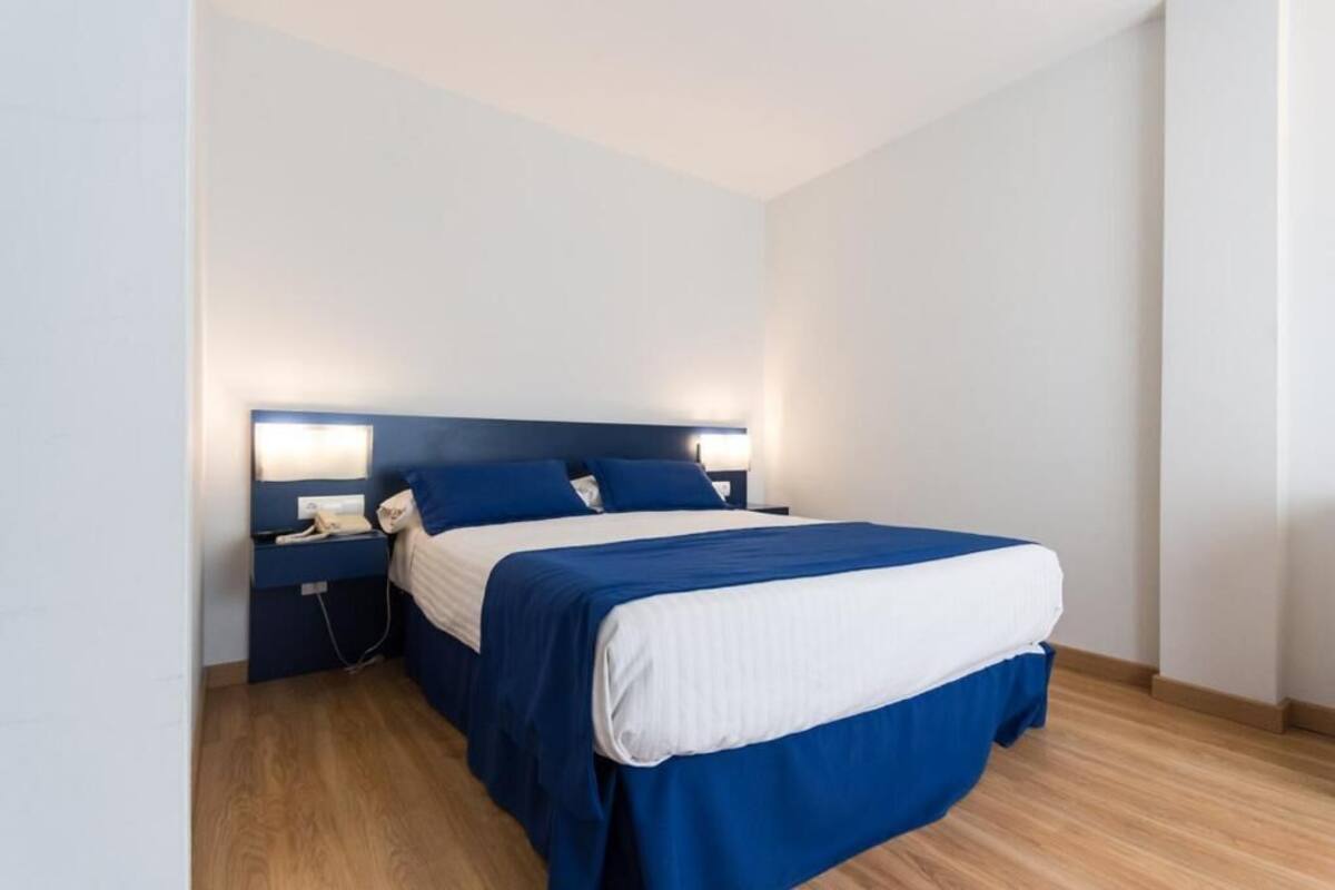 A single bed with a headboard, bedside tables, and a wall-mounted light fixture.