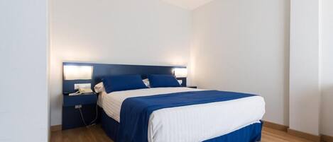 Una cama individual con cabecera, mesitas de noche y una lámpara de pared.