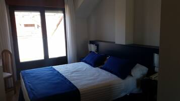 Un dormitorio con cama, una silla, una mesita de noche y una ventana.