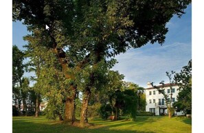 Surrounded by lush greenery, this serene property features a classic two-story building with a symmetrical facade and a front porch.