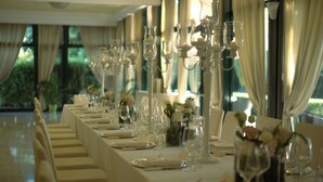 Una larga mesa de banquete dispuesta con cristalería, platos y jarrones con flores, evocando un evento de cena formal.