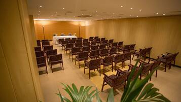 A conference room with rows of chairs facing a table with a white tablecloth and a speaker.