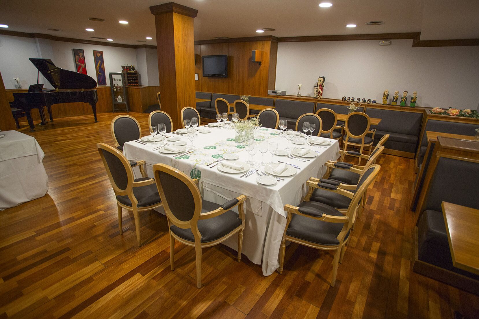 A dining area with a large round table set for a meal, surrounded by chairs with cushioned seats.