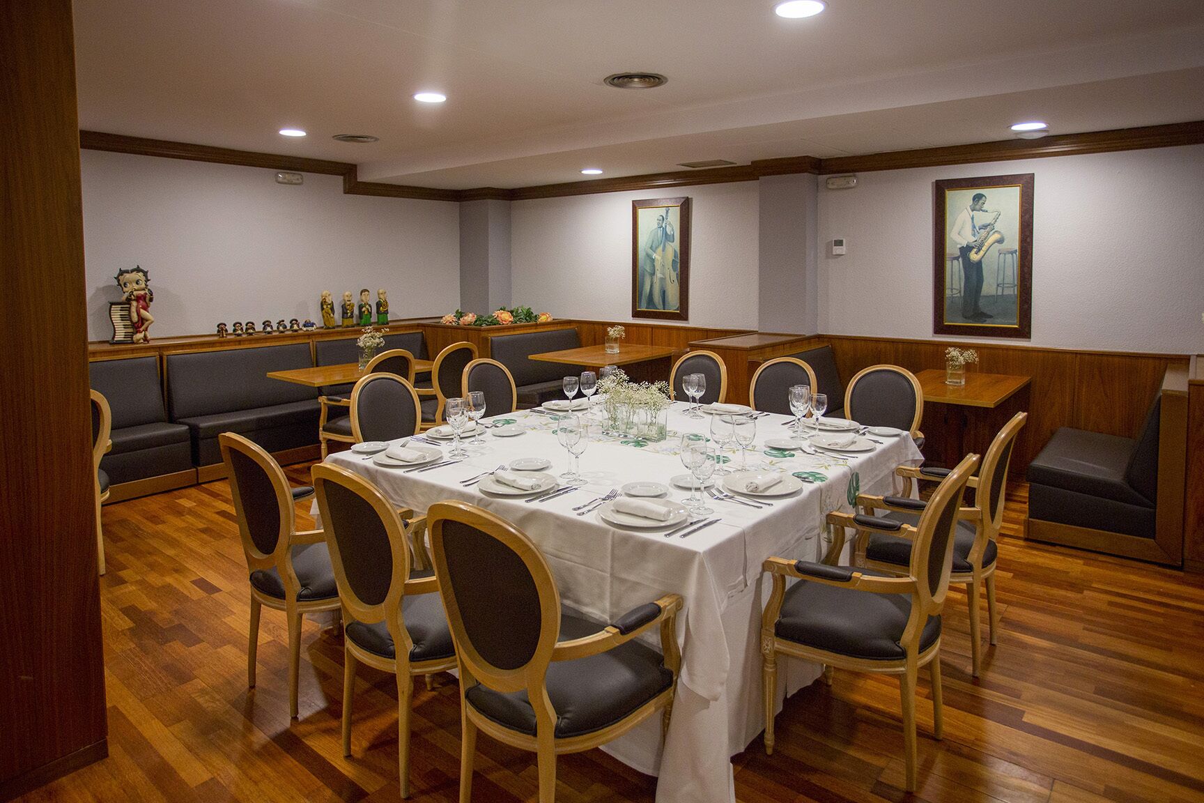 A dining area with a round table set for six, surrounded by wooden chairs with cushioned seats.