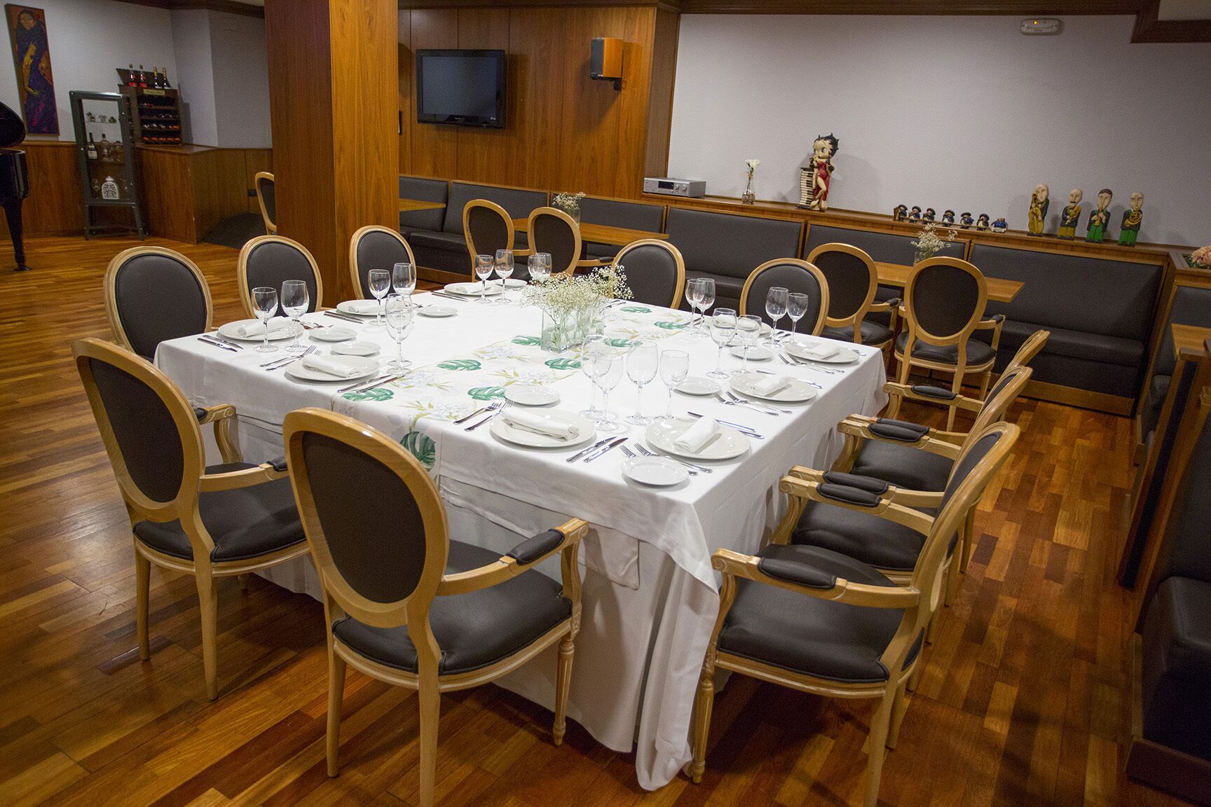 A dining area with a large round table set for a meal, surrounded by wooden chairs with cushioned seats.