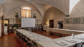 A conference room with a long table, chairs, a projector screen, and framed certificates on the wall.