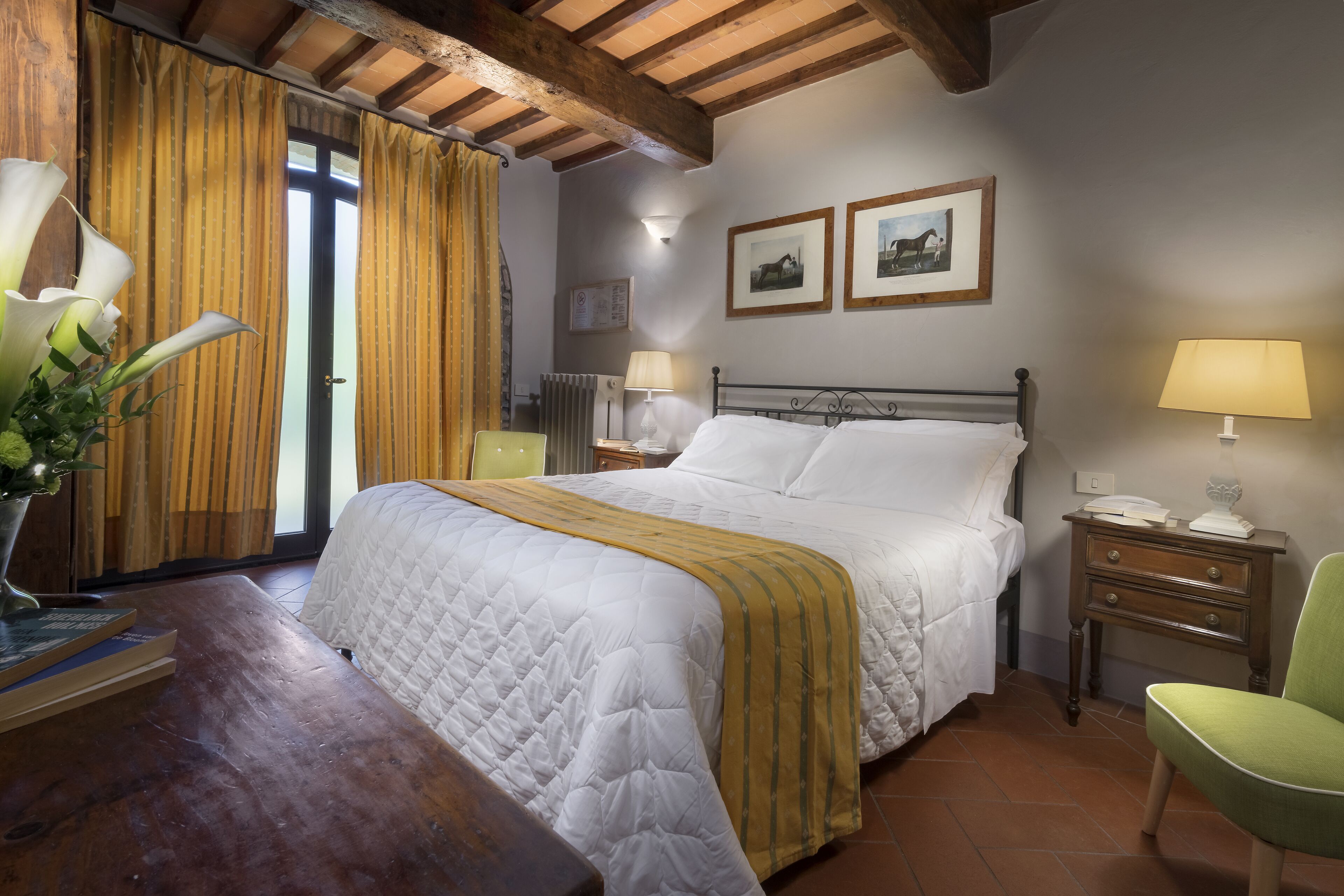 A bedroom with a bed, bedside tables, a chair, and a wooden desk.
