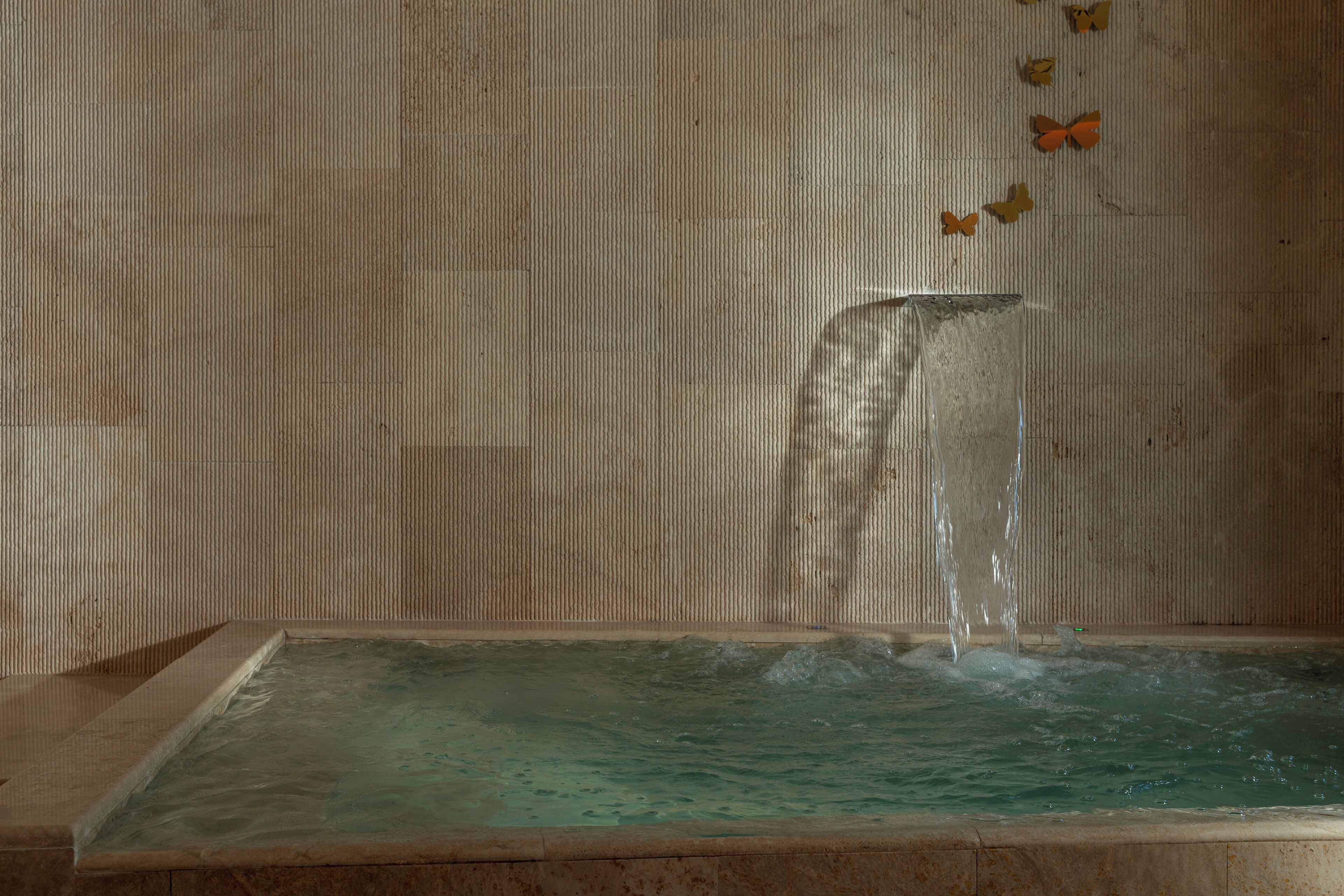 A rectangular pool with clear water and a waterfall feature.