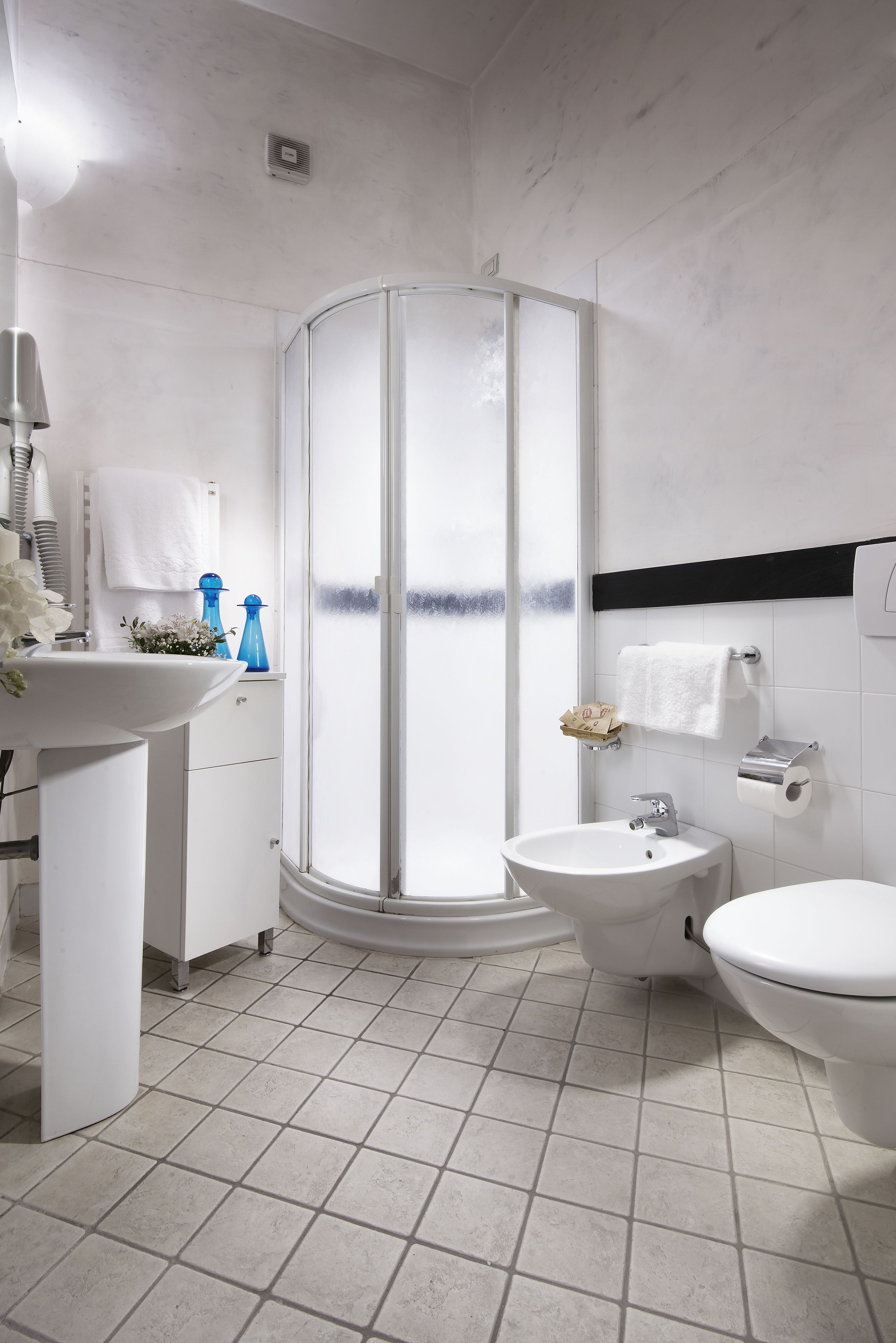 Un bagno moderno con cabina doccia, lavandino, bidet e servizi igienici.