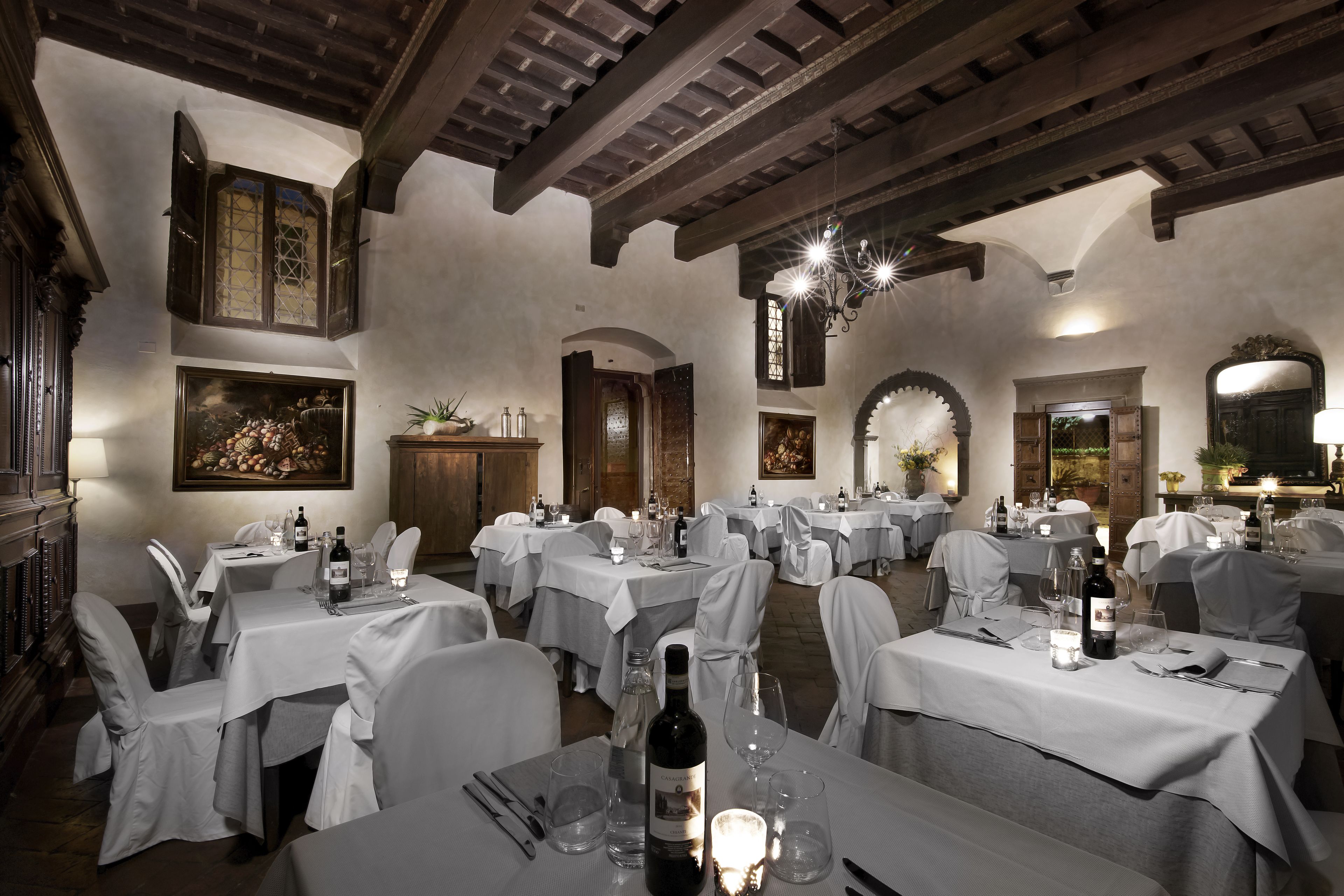 A restaurant with multiple tables set for dining, each with white tablecloths and chairs.