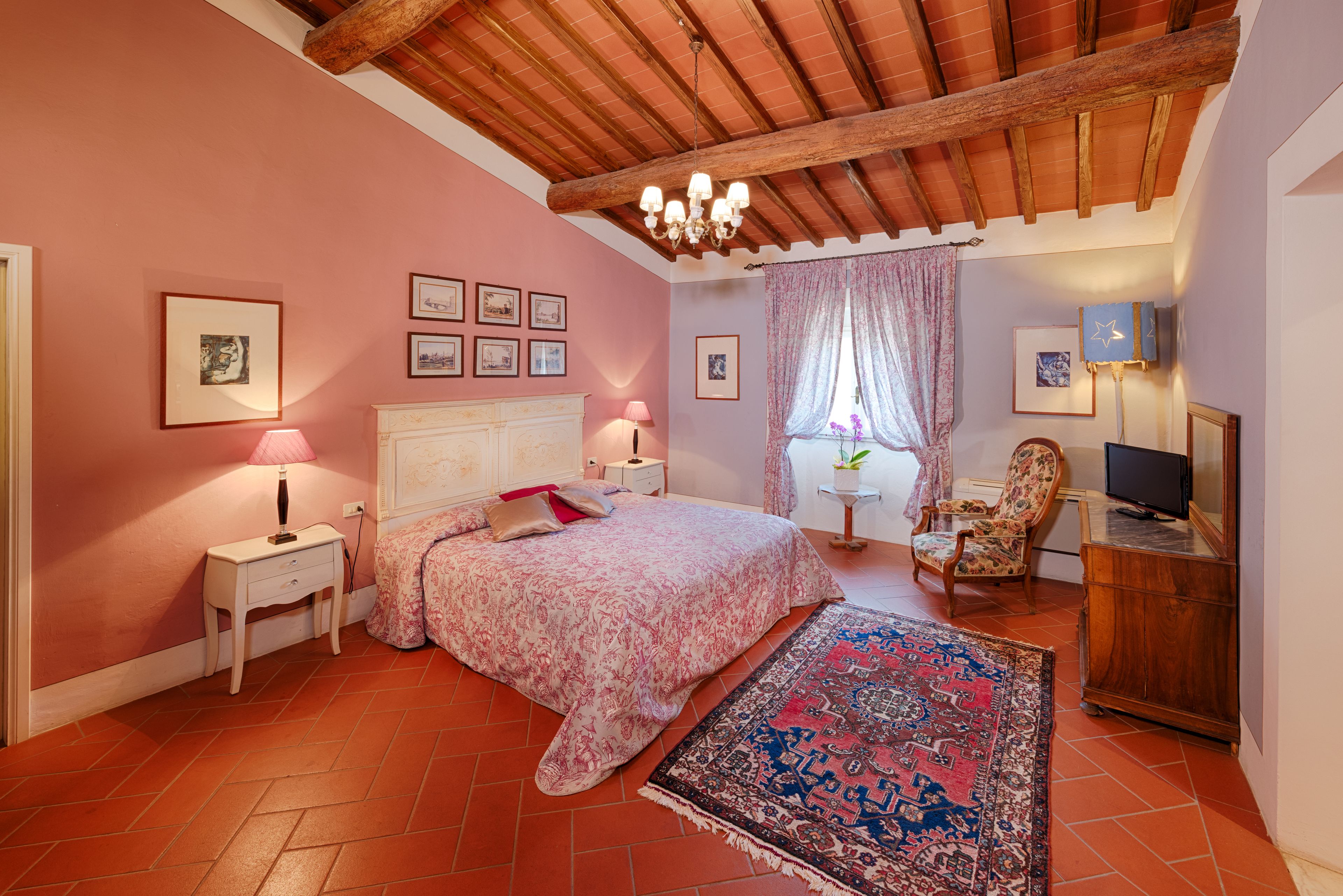 Une chambre à coucher comprenant un lit, des tables de chevet, une chaise, un bureau et un téléviseur.