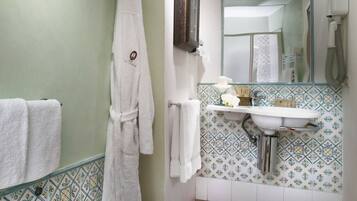 A bathroom with a sink, mirror, and a robe hanging on the wall.