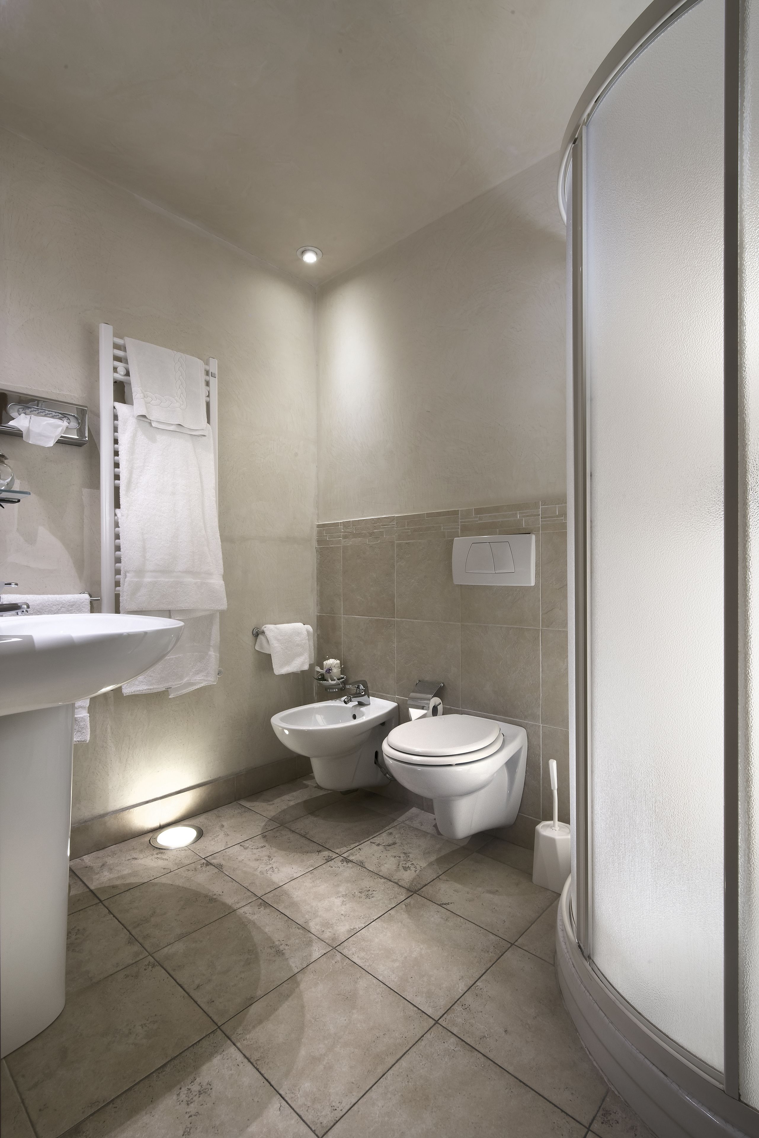 Une salle de bain moderne équipée d’un lavabo, d’un bidet, de toilettes et d’un porte-serviettes.