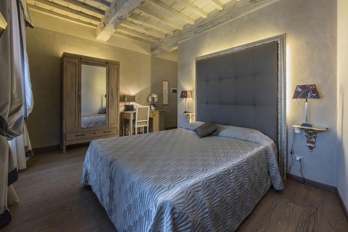Un dormitorio con una cama grande, un armario, un escritorio y un espejo.