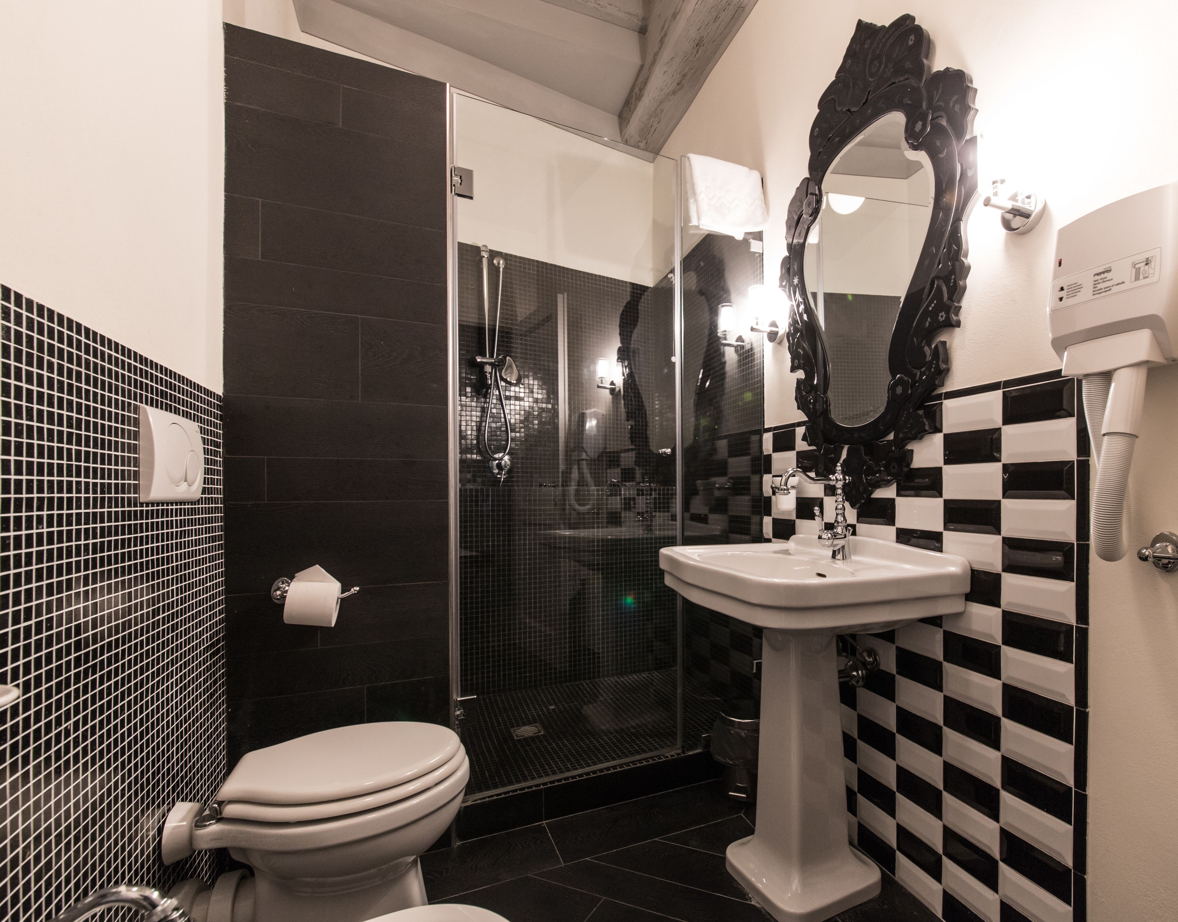 Un baño con inodoro, lavabo, ducha y un espejo grande.
