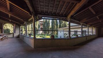 An open courtyard with a wooden ceiling, columns, and potted plants.