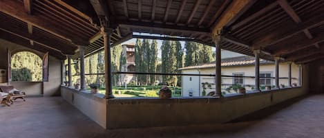 An open courtyard with a wooden ceiling, columns, and potted plants.