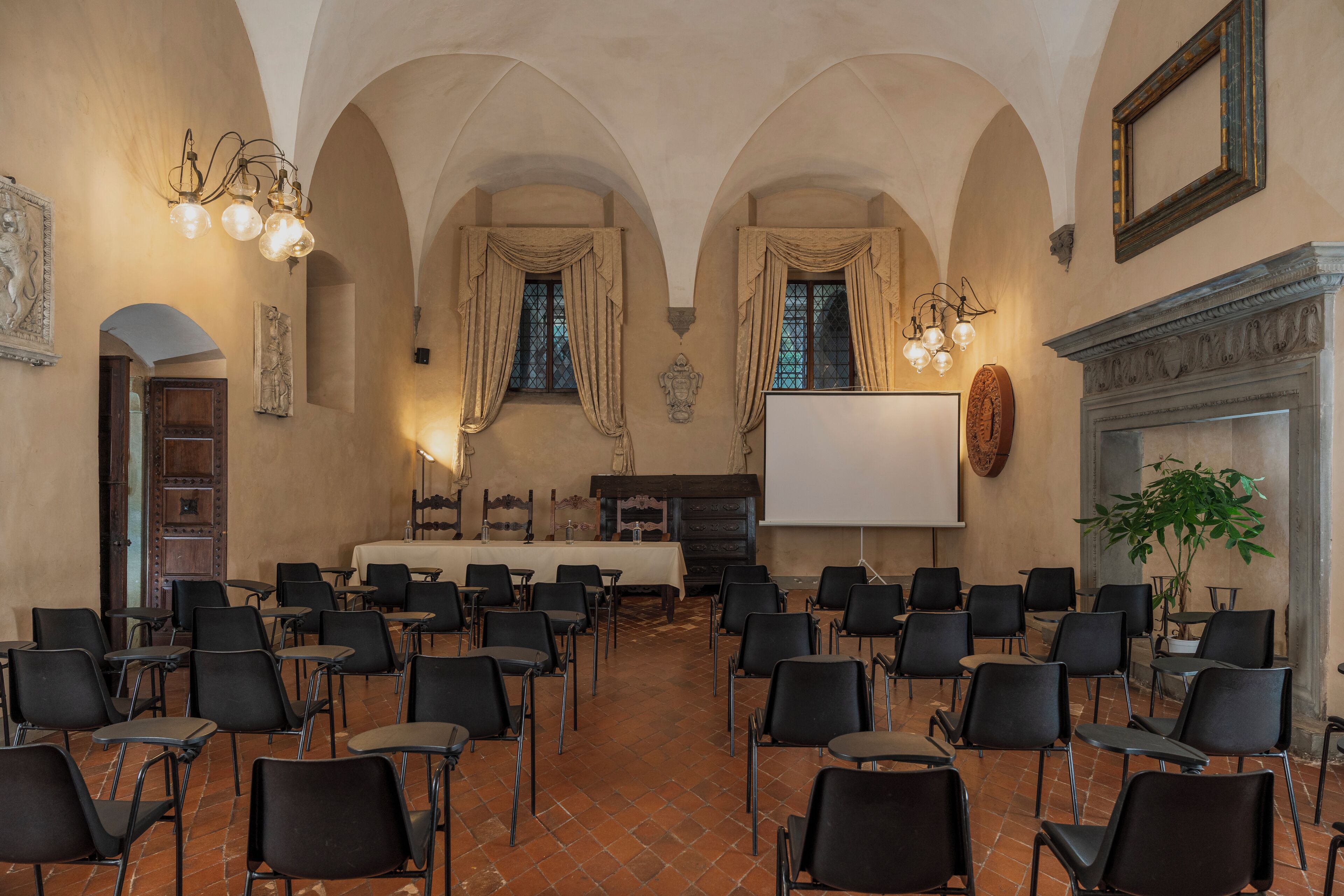A conference room with a long table, chairs, a projector screen, and a fireplace.