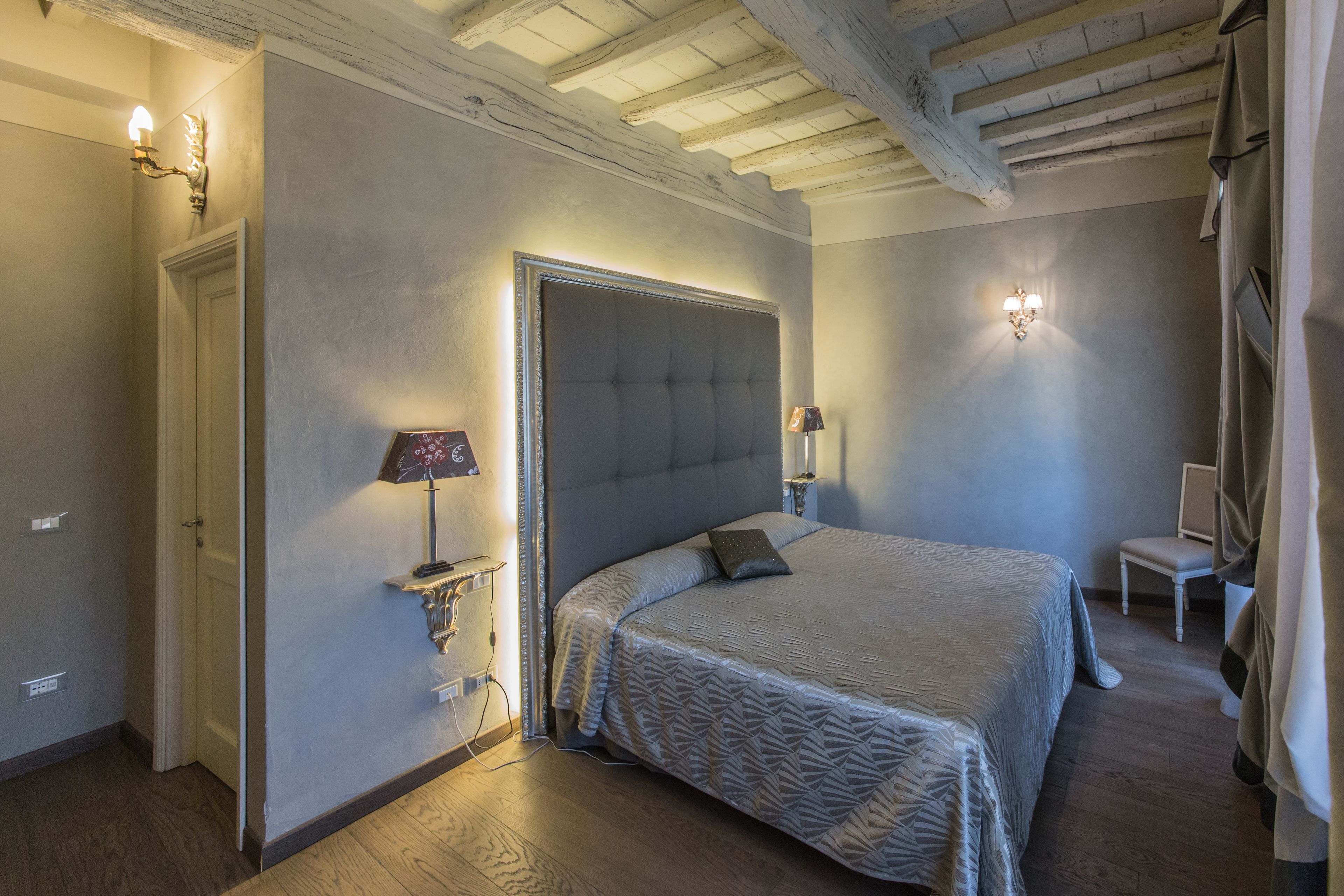 Ein Schlafzimmer mit einem großen Bett, einer Tür, einem Sessel und einer Wandlampe.